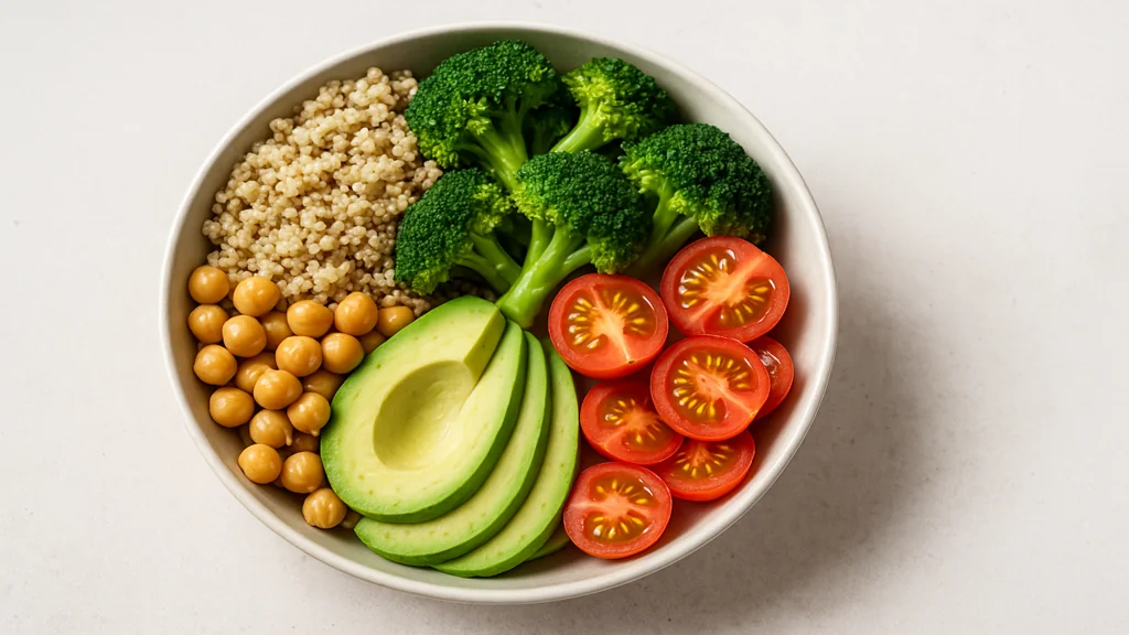 Bol repas anti-inflammatoire vu du dessus avec quinoa, brocoli, pois chiches, avocat et tomates cerises, illustrant une assiette saine pour favoriser la perte de poids 