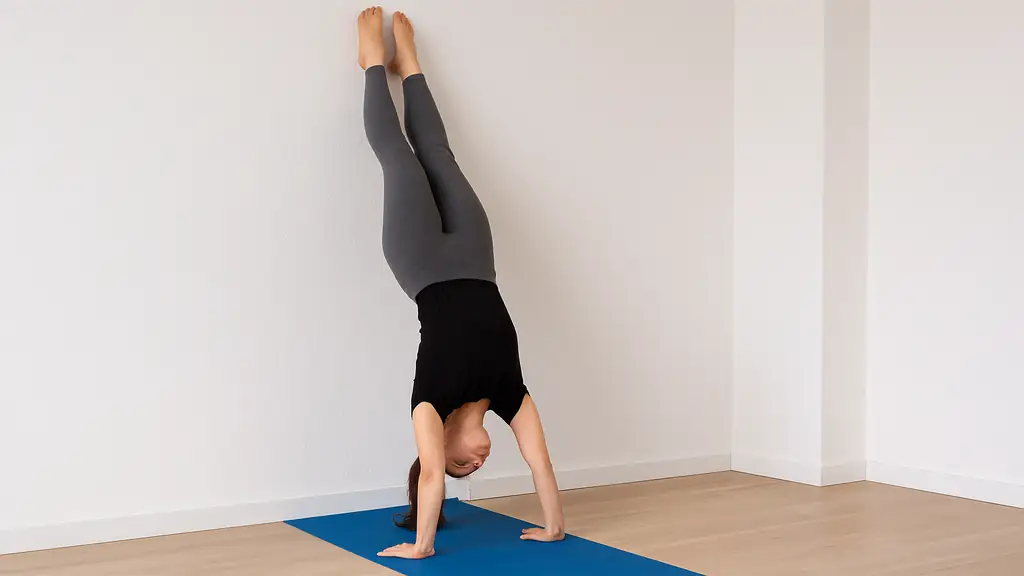 Femme réalisant un handstand contre un mur pour apprendre l’équilibre sur les mains en toute sécurité