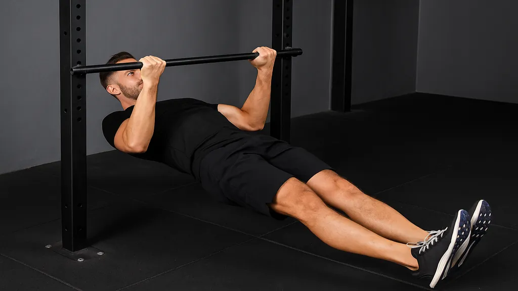 Traction australienne réalisée sous une barre fixe en salle de sport, exercice de tirage horizontal sollicitant le dos, les bras et le gainage