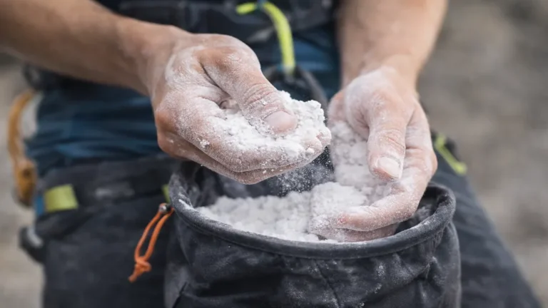 Mains couvertes de magnésie sportive prenant de la poudre dans un sac à magnésie, amélioration de l’adhérence en escalade et musculation