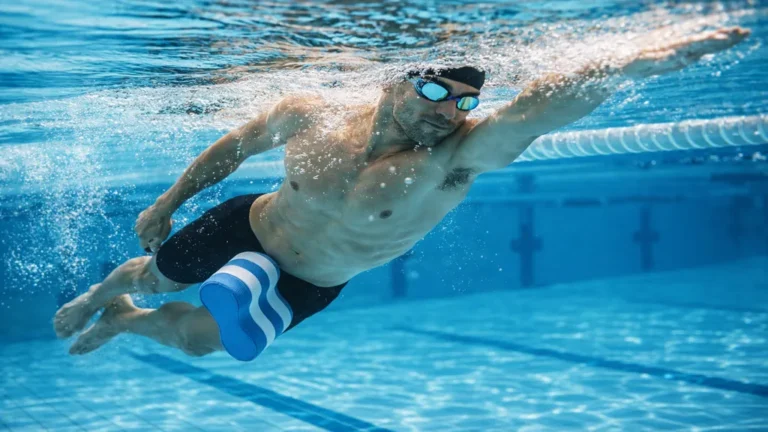 Nageur effectuant un crawl avec pull buoy entre les cuisses, travail des bras en natation, position horizontale et gainage en piscine