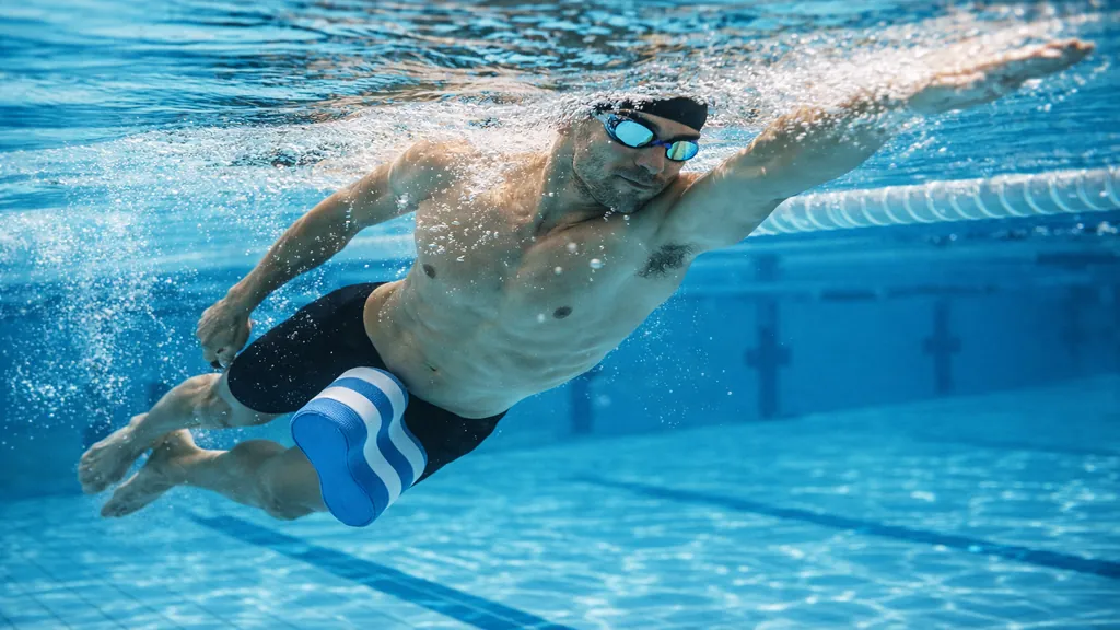 Nageur effectuant un crawl avec pull buoy entre les cuisses, travail des bras en natation, position horizontale et gainage en piscine
